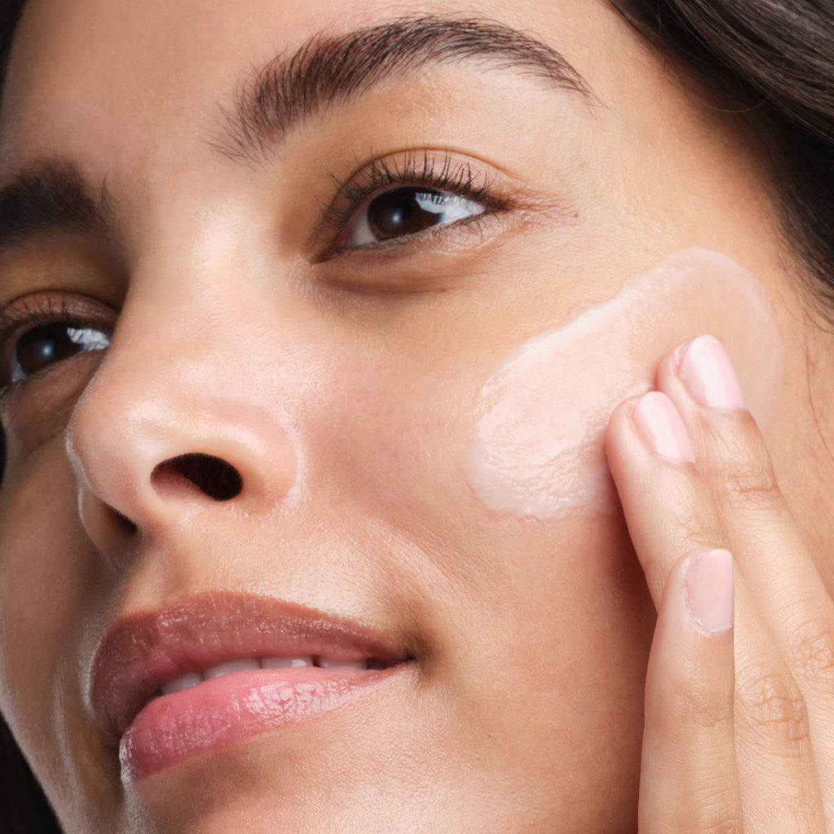 Shot of model pumping The Dewy Serum onto hands.